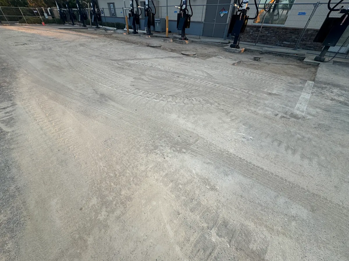 A large paved lot with tire marks, dirty patches and construction fencing.