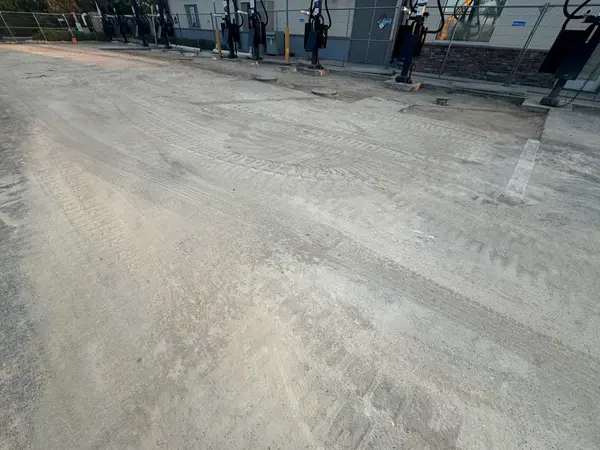 A large paved lot with tire marks, dirty patches and construction fencing.